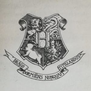 Blason de Poudlard sur lequel on peut lire en latin : Draco Dormiens Nunquam Titilandus.