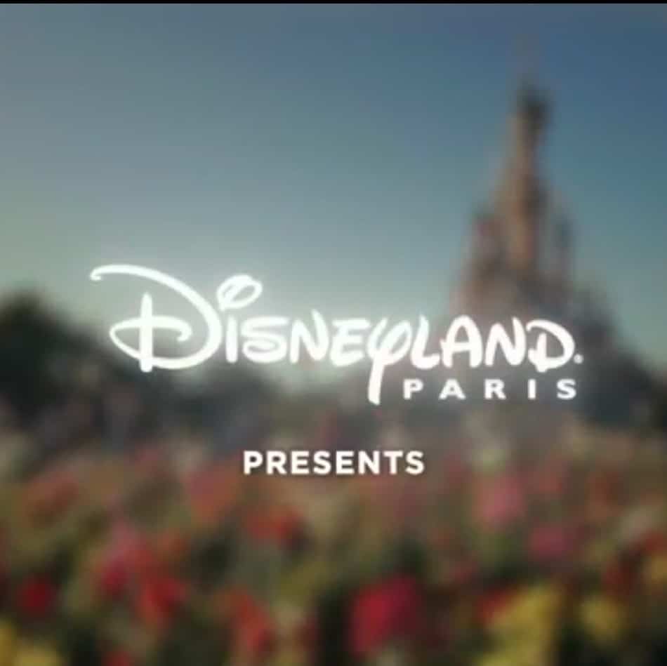 "Disneyland Paris" est écrit en blanc. On peut voir en arrière-plan le château de La Belle au Bois Dormant.