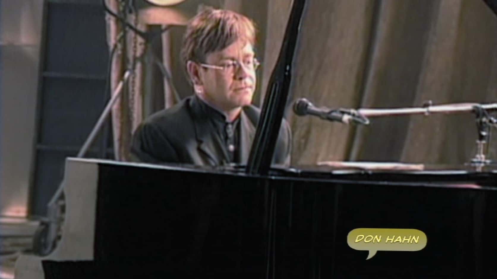 Elton John, assis devant un piano, travaille sur la musique du Roi Lion.