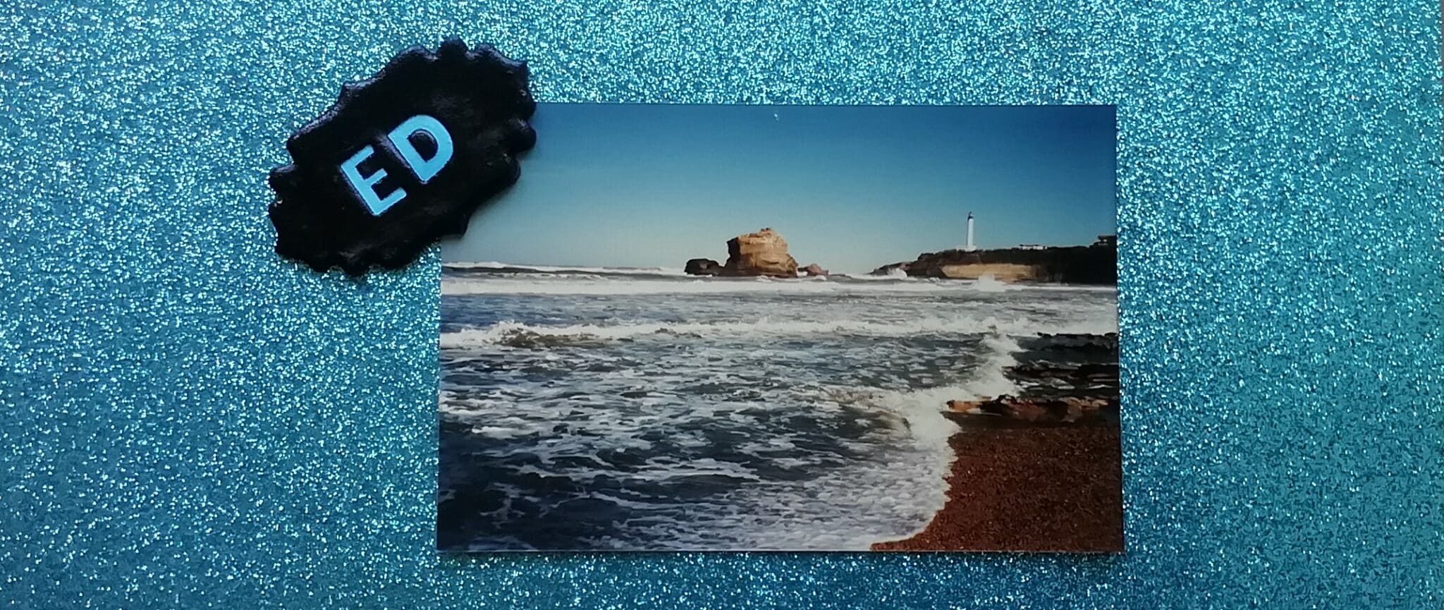 La photo d'une plage est présente sur un fond bleu pailleté.