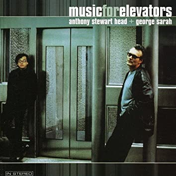 La couverture de l'album met en avant Anthony Stewart Head et George Sarah qui se tiennent devant un ascenseur.