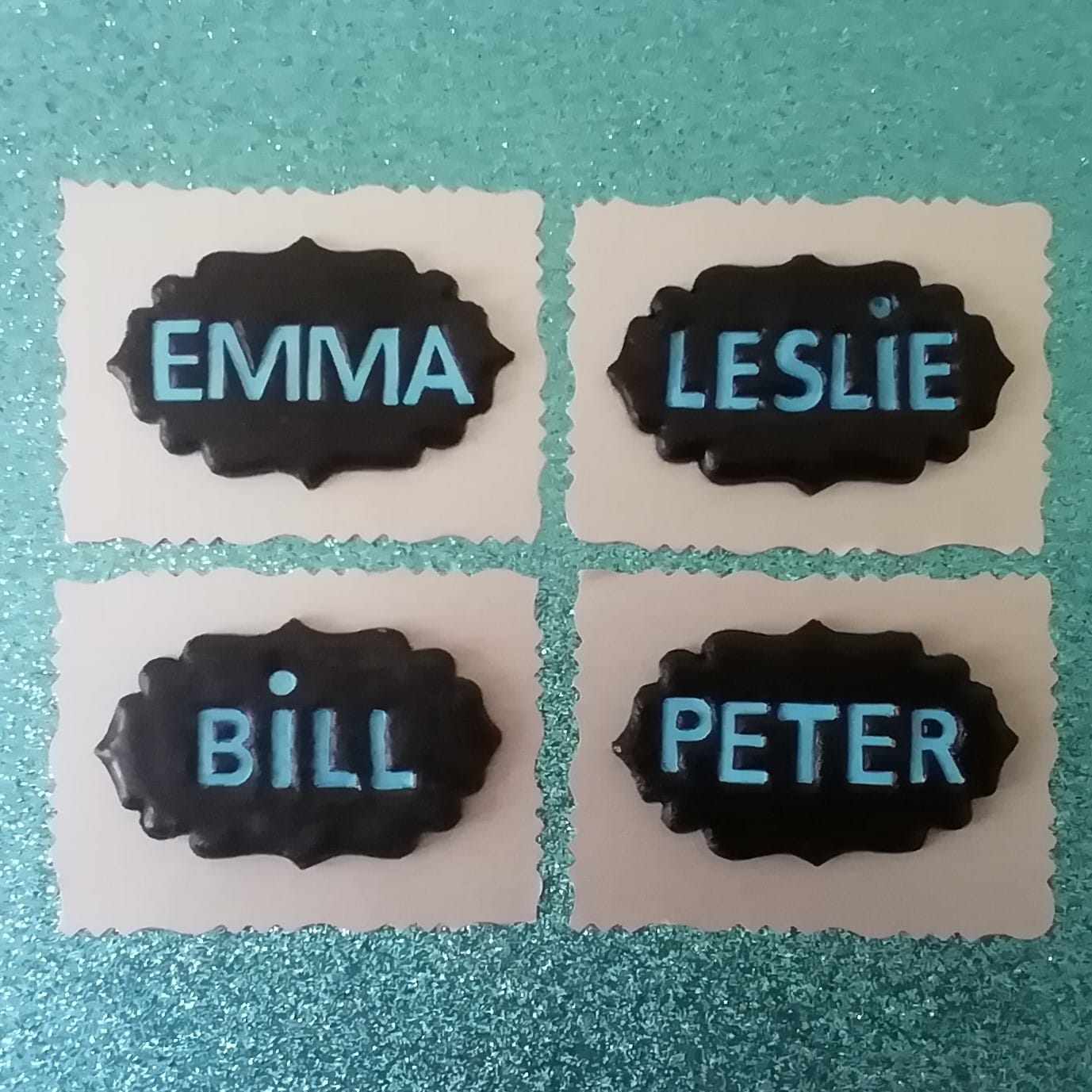 Les prénoms Emma, Leslie, Bill et Peter ont été réalisés en pâte polymer et ont été disposés côte à côte sur un fond bleu.