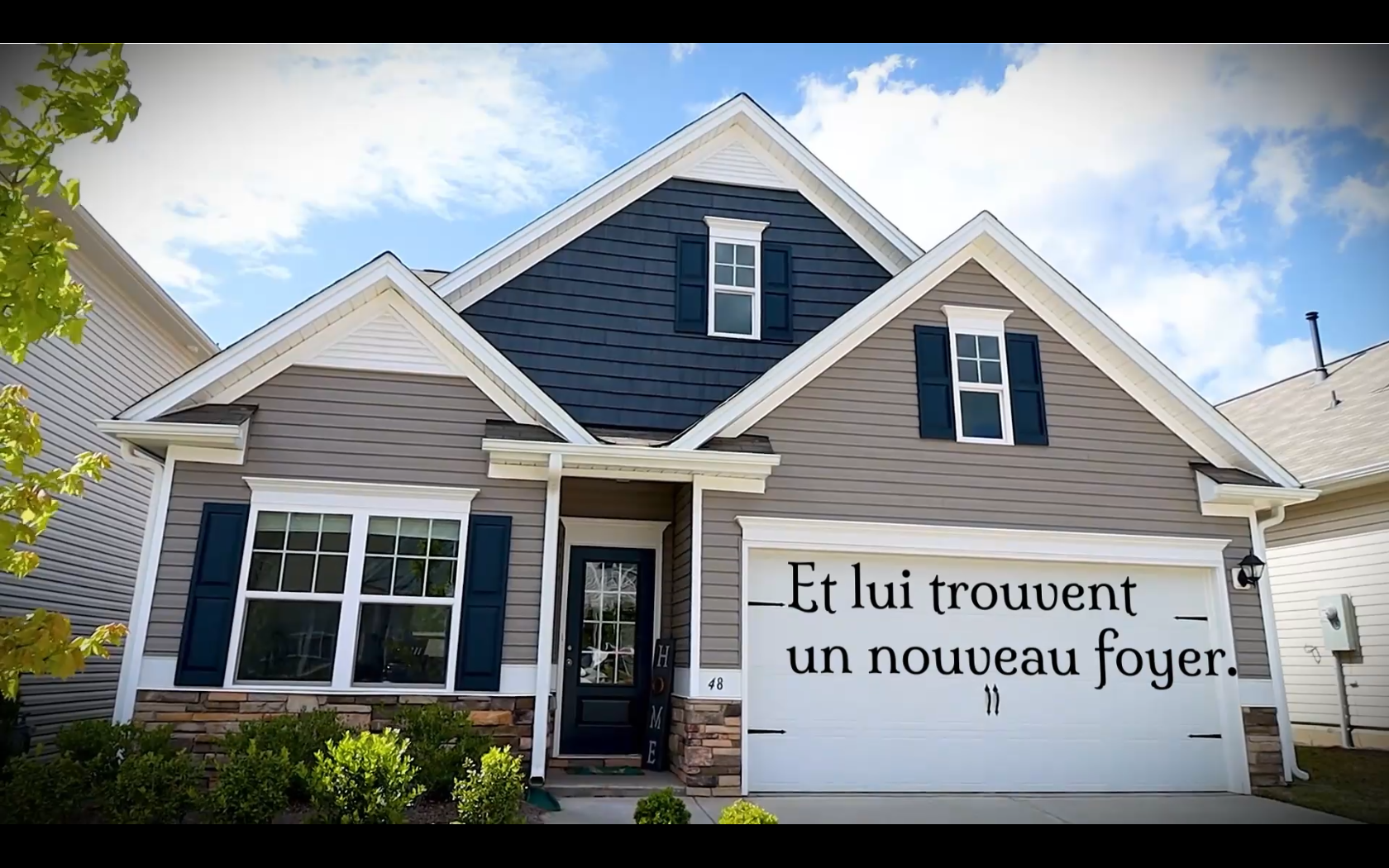 Cette maison présente une porte de garage blanche sur laquelle est écrite "Et lui trouvèrent un nouveau foyer".