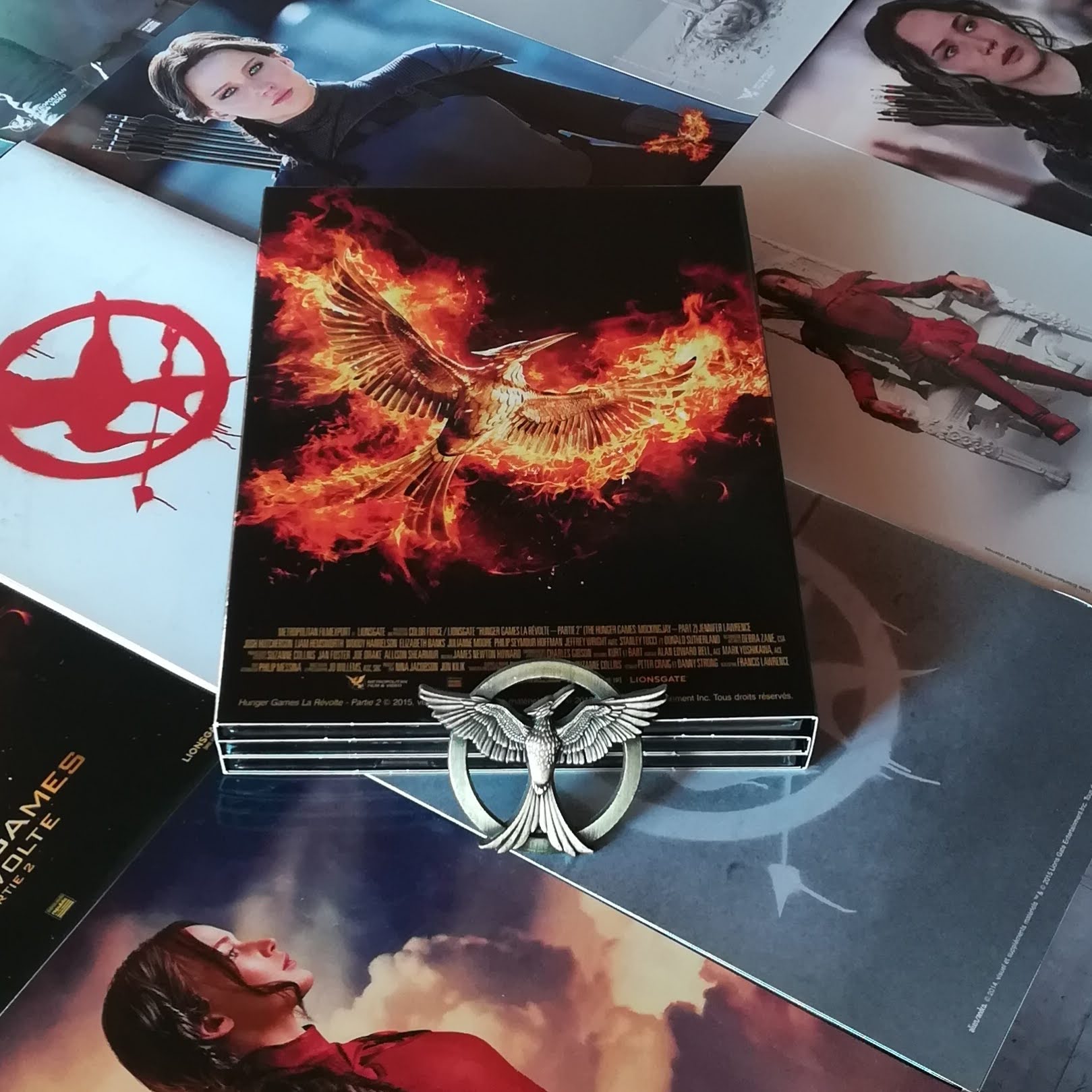 Un porte-clé qui représente le gea moqueur est posé sur un coffret blu-ray de la saga Hunger Games.